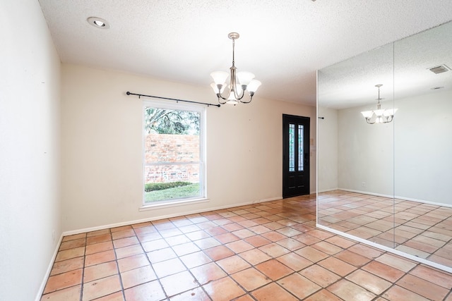 spare room with light tile patterned flooring, visible vents, a textured ceiling, and an inviting chandelier