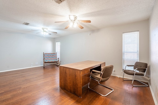 home office featuring dark wood finished floors, visible vents, ceiling fan, a textured ceiling, and baseboards