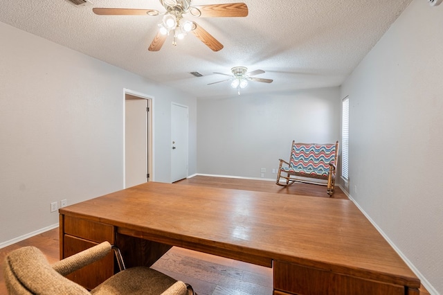 office with a textured ceiling, wood finished floors, visible vents, and baseboards