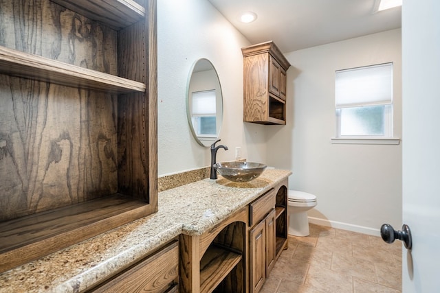 bathroom with baseboards, vanity, and toilet