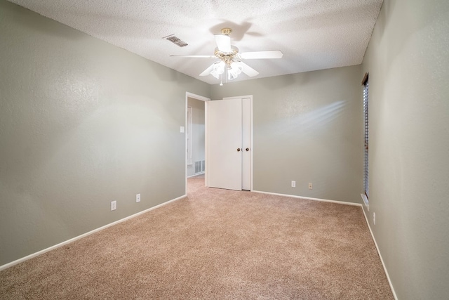 spare room with light carpet, ceiling fan, baseboards, and a textured ceiling