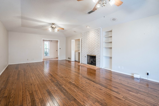 unfurnished living room with built in features, a brick fireplace, a textured ceiling, and wood finished floors