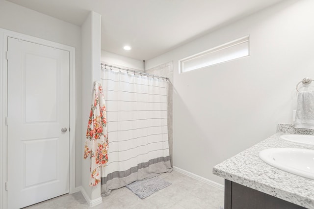 bathroom featuring double vanity, a sink, and baseboards