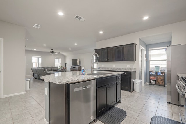 kitchen with visible vents, appliances with stainless steel finishes, open floor plan, a sink, and an island with sink