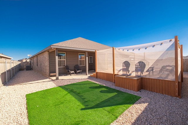 back of property with a fenced backyard, a shingled roof, and a patio