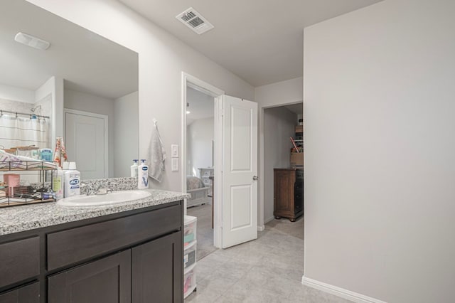 bathroom with a closet, visible vents, connected bathroom, vanity, and baseboards