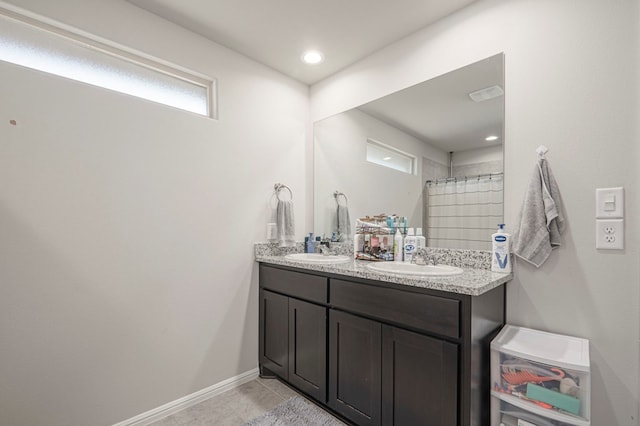 bathroom featuring double vanity, curtained shower, baseboards, and a sink