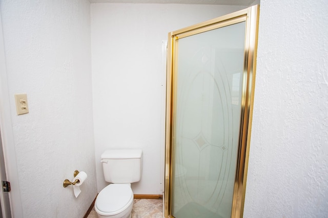 bathroom featuring tile patterned flooring, toilet, and a shower with door