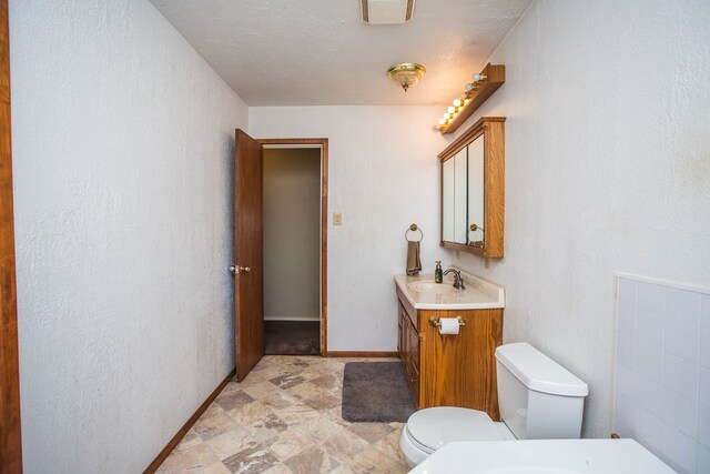 bathroom featuring a textured ceiling, vanity, and toilet