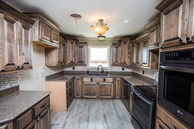 kitchen featuring black appliances, decorative backsplash, light hardwood / wood-style floors, and sink