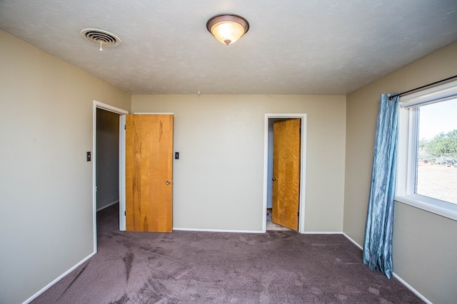 unfurnished bedroom with a closet and dark carpet