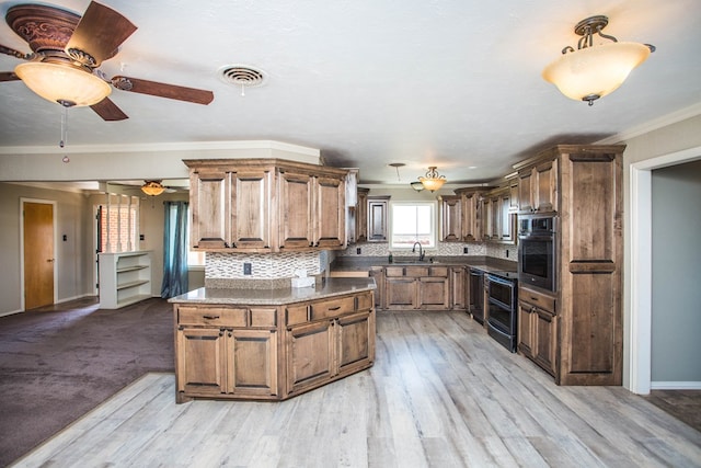 kitchen featuring stainless steel oven, crown molding, sink, light wood-type flooring, and tasteful backsplash