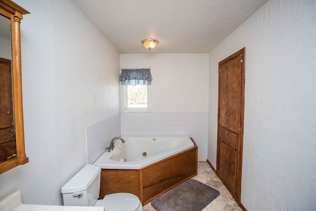 bathroom with a textured ceiling, toilet, and a tub