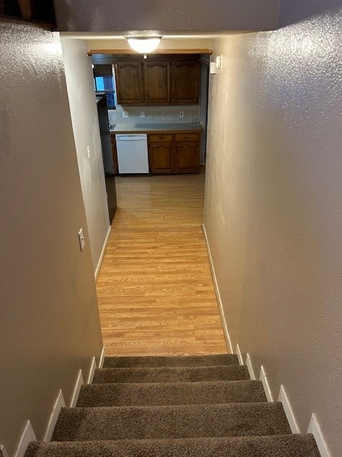 stairs with baseboards, a textured wall, and wood finished floors