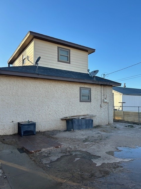 view of side of home featuring stucco siding and fence