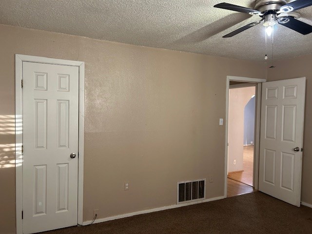 empty room with visible vents, ceiling fan, a textured ceiling, and carpet