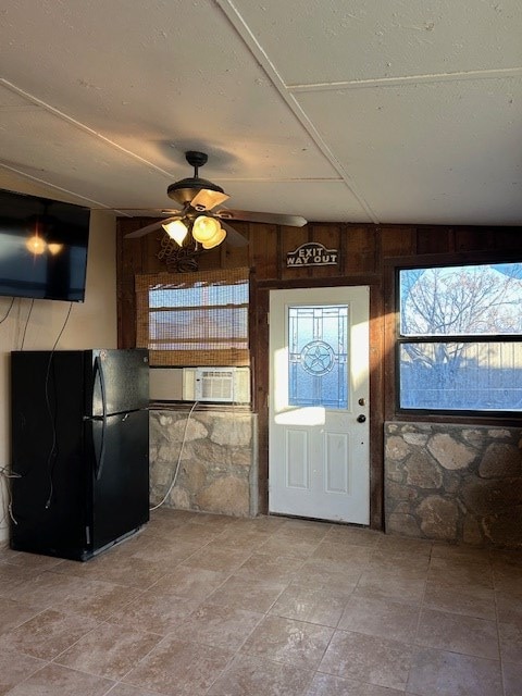 entrance foyer featuring ceiling fan, cooling unit, a textured ceiling, and wood walls