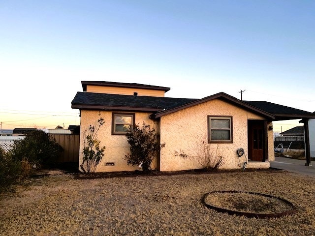 back of property with a shingled roof, crawl space, fence, and stucco siding