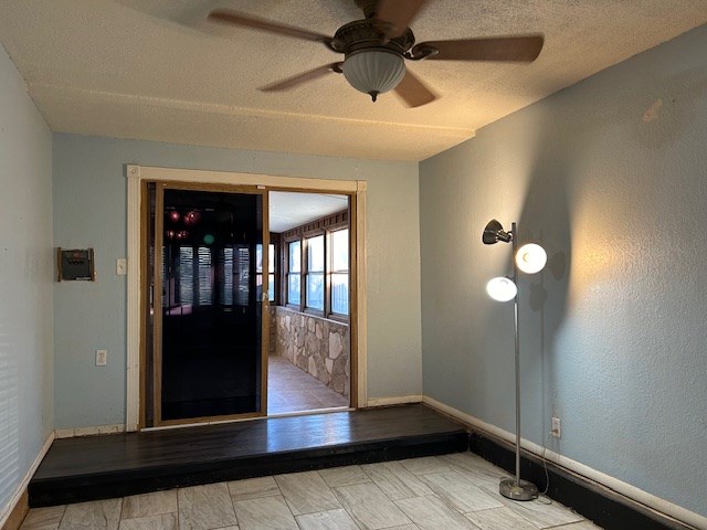 entryway featuring a textured ceiling, baseboards, and a ceiling fan