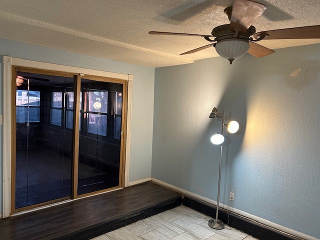 unfurnished room featuring baseboards, a textured ceiling, and a textured wall
