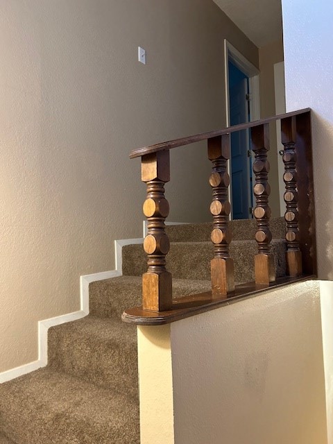 stairway featuring baseboards and a textured wall