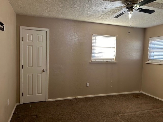 empty room featuring a ceiling fan, baseboards, a textured ceiling, and carpet flooring