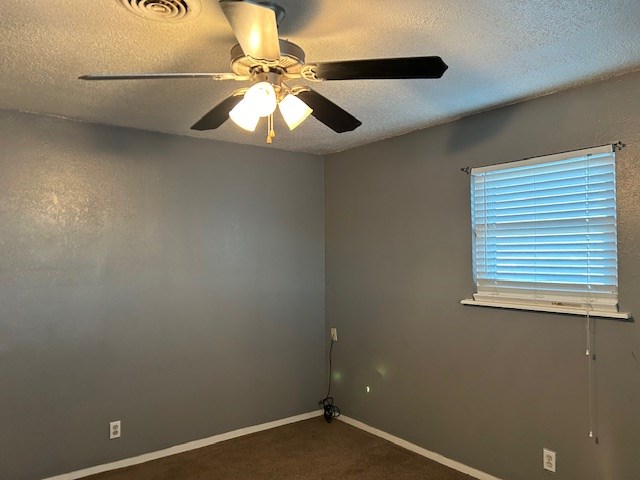 carpeted empty room featuring a ceiling fan, baseboards, visible vents, and a textured ceiling