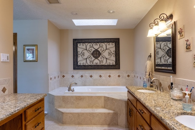 bathroom with double vanity, a textured ceiling, a bath, a sink, and a skylight