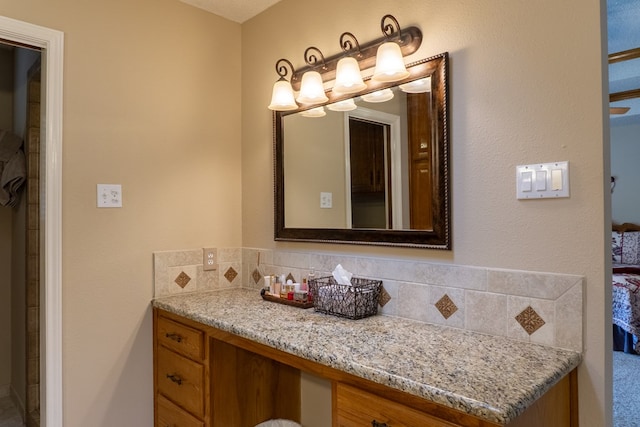 ensuite bathroom featuring backsplash, vanity, and ensuite bath