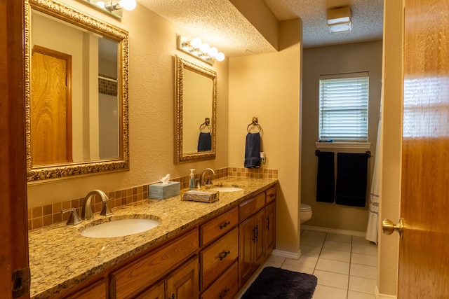 bathroom featuring a sink, tile patterned floors, toilet, and a textured ceiling