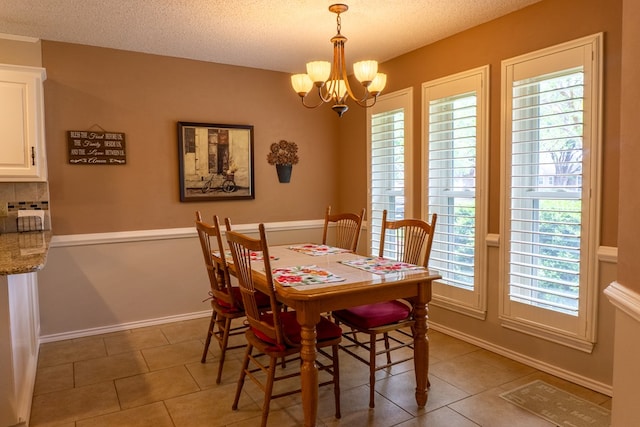 dining area featuring a textured ceiling, light tile patterned floors, a chandelier, and a healthy amount of sunlight