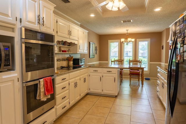 kitchen with a textured ceiling, ceiling fan with notable chandelier, black appliances, and white cabinetry