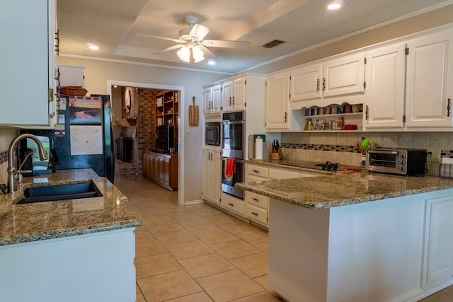 kitchen with a sink, light stone counters, tasteful backsplash, and black appliances