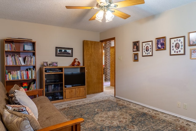 carpeted living area featuring baseboards, a ceiling fan, and a textured ceiling