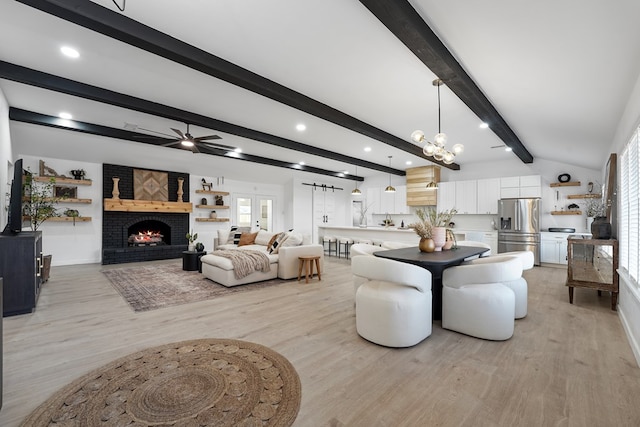 dining space with a brick fireplace, vaulted ceiling with beams, ceiling fan with notable chandelier, and light hardwood / wood-style floors