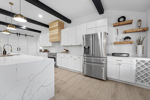 kitchen featuring sink, high quality appliances, white cabinets, decorative light fixtures, and a barn door