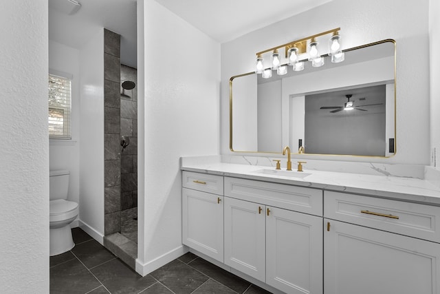 bathroom featuring vanity, tiled shower, ceiling fan, and toilet