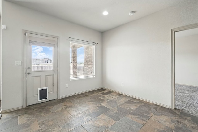 foyer featuring stone tile floors, recessed lighting, and baseboards