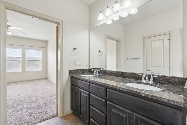 bathroom featuring ceiling fan, double vanity, and baseboards