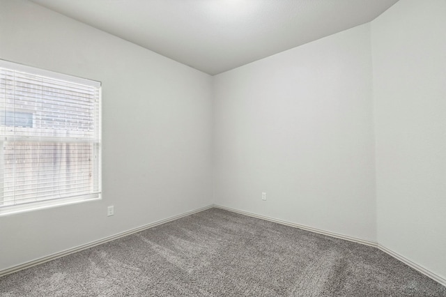 carpeted empty room featuring baseboards