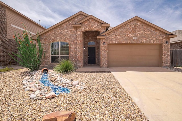 view of front facade featuring brick siding, an attached garage, driveway, and fence