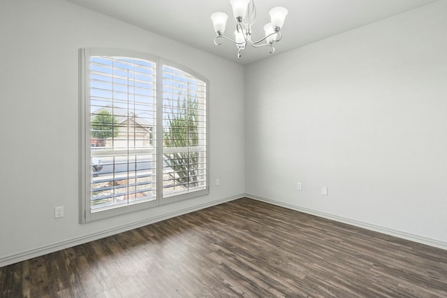 empty room with dark wood-style floors, a chandelier, and baseboards