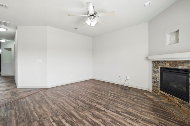 unfurnished living room with wood finished floors, ceiling fan, baseboards, and a stone fireplace