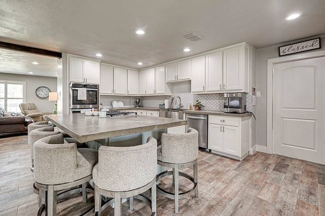 2804 W Dengar Ave, Midland, TX 79705 - kitchen with stainless steel appliances, a sink, a kitchen bar, white cabinets, and recessed lighting