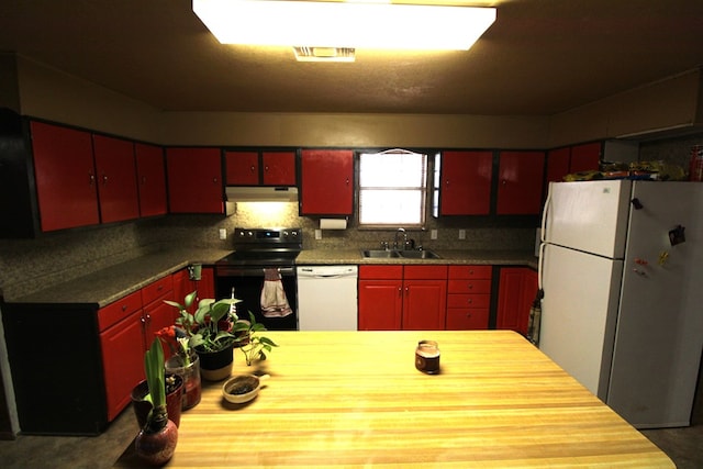 kitchen featuring visible vents, a sink, white appliances, under cabinet range hood, and red cabinetry
