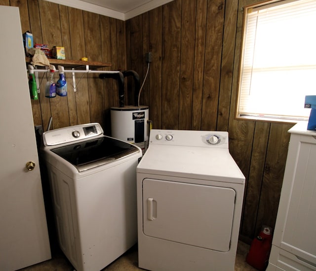 washroom with electric water heater, wood walls, washer and dryer, and laundry area