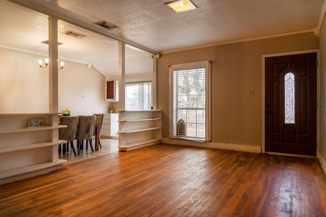 foyer entrance featuring ornamental molding, dark wood-type flooring, a textured ceiling, and an inviting chandelier