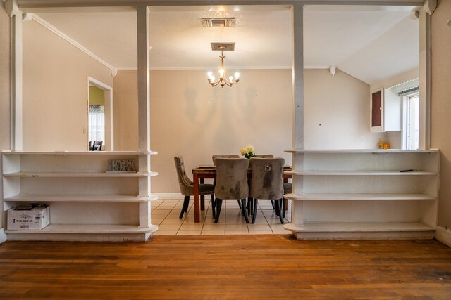 tiled dining space featuring lofted ceiling, crown molding, and a chandelier