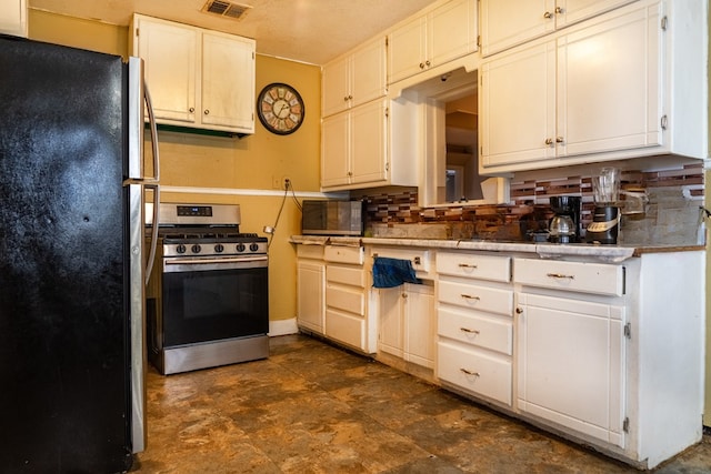 kitchen featuring white cabinetry, tasteful backsplash, a textured ceiling, black refrigerator, and stainless steel stove