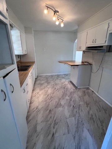 kitchen featuring white cabinetry, kitchen peninsula, sink, and tasteful backsplash